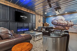 Un espace de détente moderne avec des canapés en cuir, un téléviseur à écran plat et une grande fresque représentant un dirigeable.