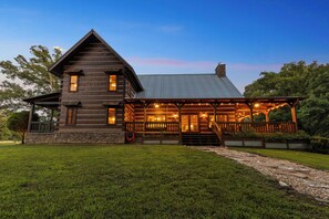 A log cabin with a porch and a stone foundation.