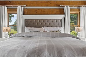 A bedroom with a large bed, a tufted headboard, and two bedside lamps.