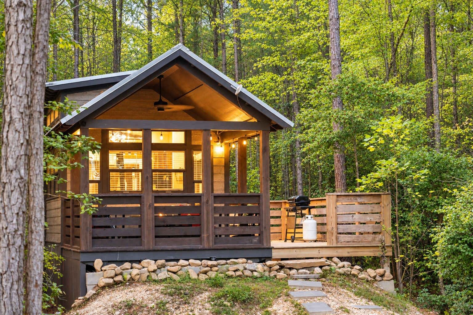 A cabin with a wooden deck, a fireplace, and a grill area.