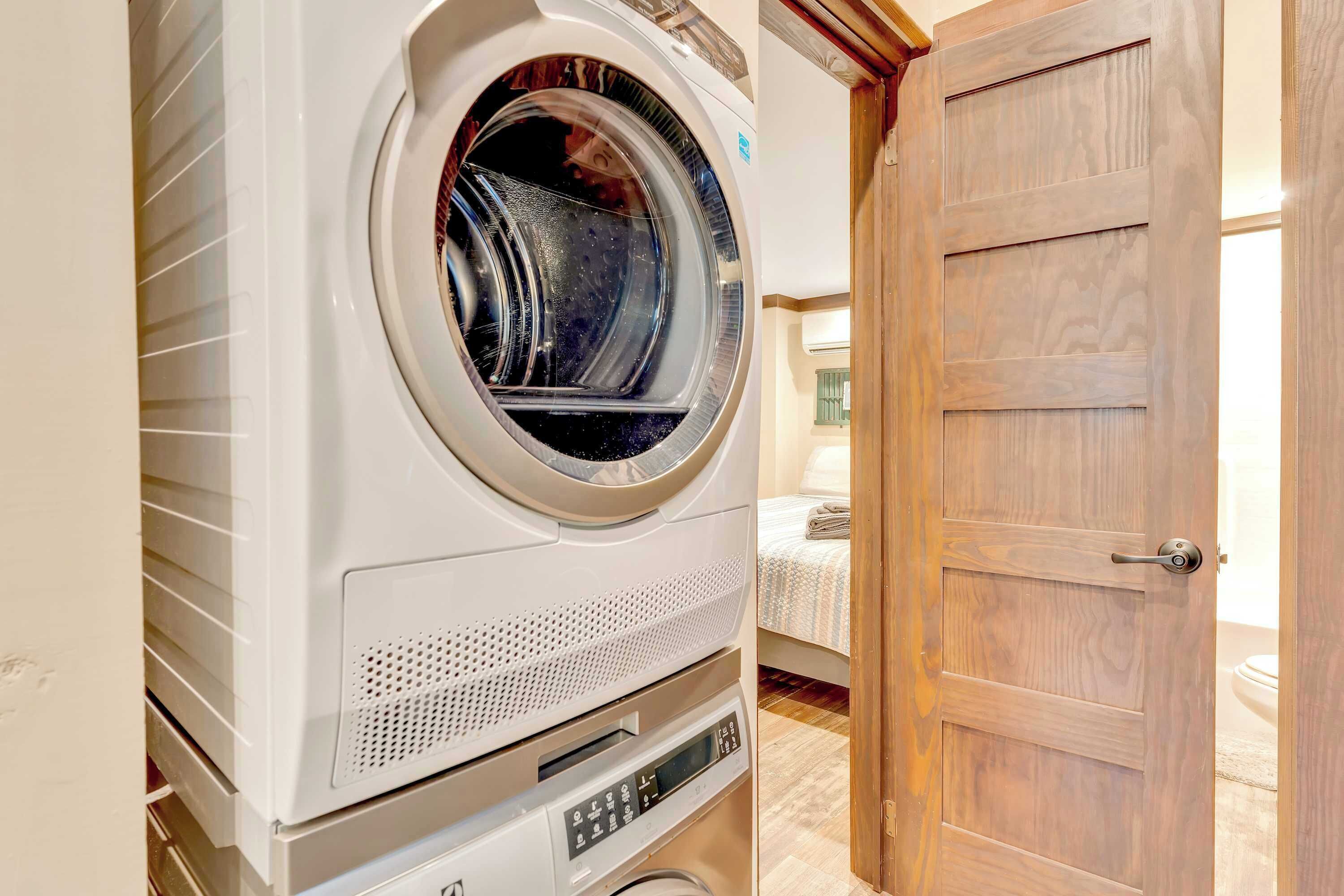 Un lave-linge à chargement frontal dans une buanderie, avec une porte en bois.