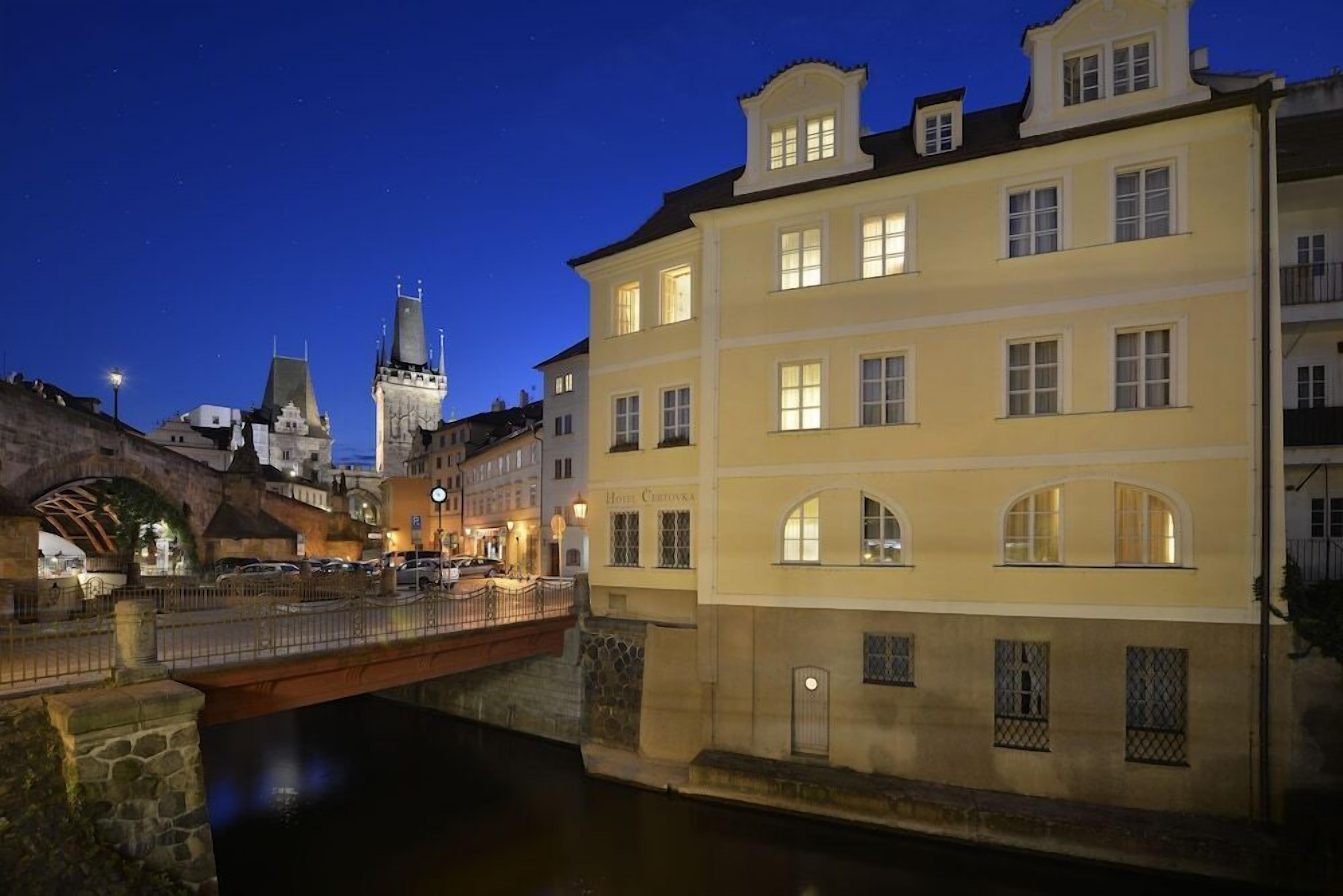 A historic building with multiple stories, a clock tower, and a bridge over a canal.