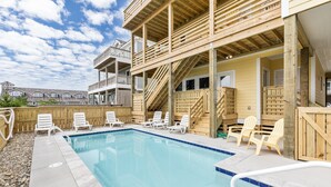 Un espace piscine avec des chaises longues blanches et une terrasse en bois.