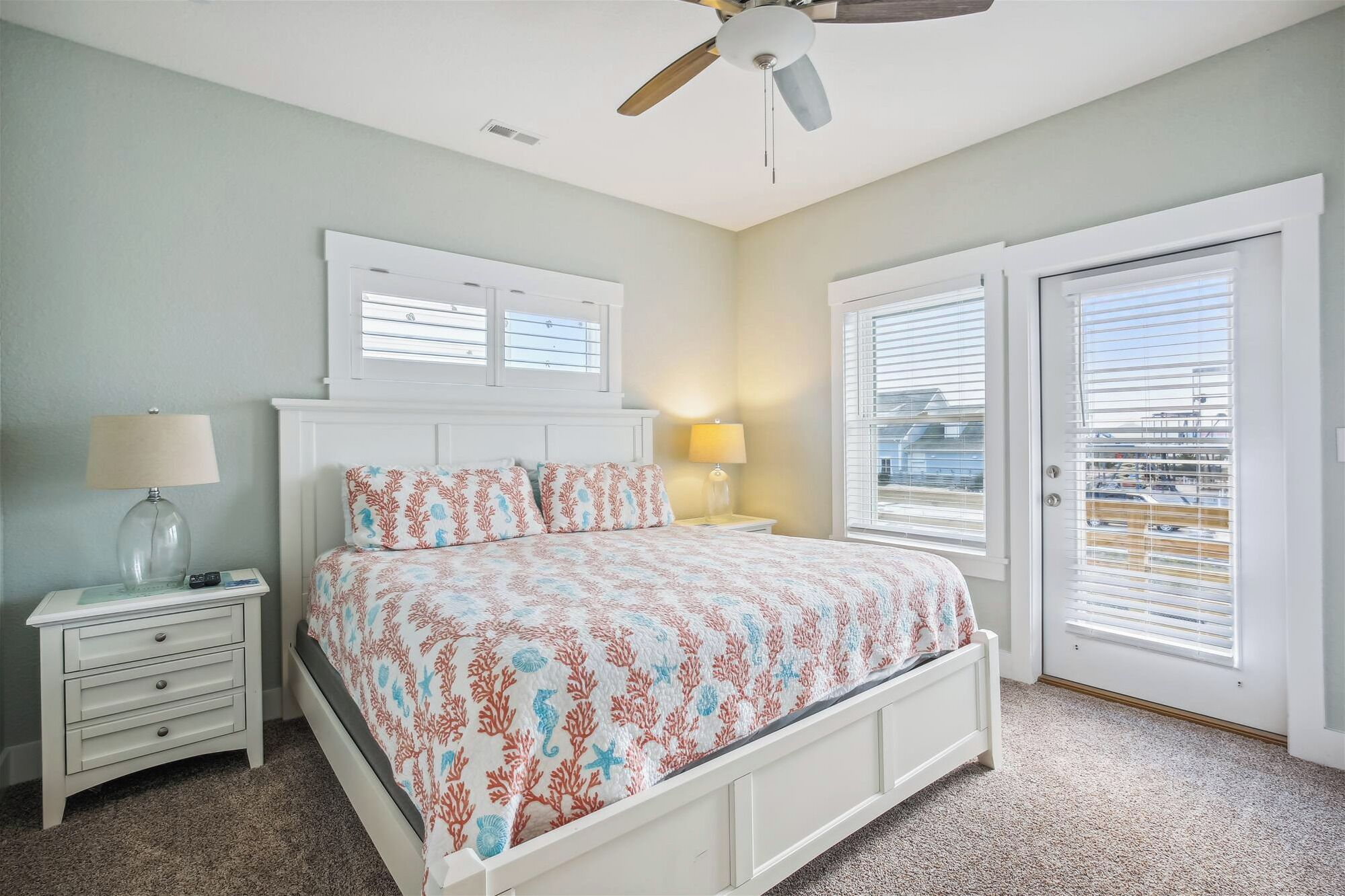 A bedroom with a bed, two bedside tables, a ceiling fan, and a view through the door.
