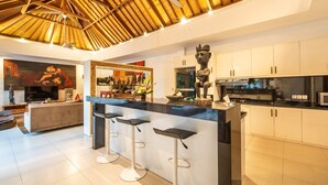 A modern kitchen with a central island, bar stools, and a decorative sculpture. - Fabulous Private Villa, 3 BR, Canggu With Staff (Tibubeneng)