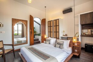 A bedroom with a large bed, wooden headboard, a mirror, and a small desk with a lamp. - Tropical Private Villa, 3 BR, Canggu Ricefield View (Canggu)
