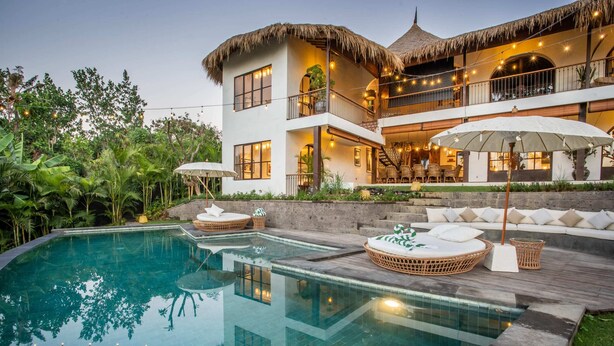 A modern house with a large swimming pool, outdoor seating, and a thatched-roof balcony. - Majestic Private Villa, 6 BR, Canggu With Staff (Canggu)