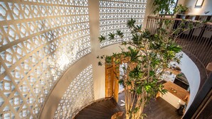 A spiral staircase with a wooden finish, surrounded by a lattice structure and a potted plant. - Majestic Private Villa, 6 BR, Canggu With Staff (Canggu)