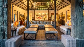 A spacious living area with a high ceiling, wicker furniture, and a large painting.