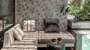A modern outdoor seating area with a patterned wall, a woven ceiling, and a view of greenery. - Batukaru Private Pool Suite 2 (Canggu)