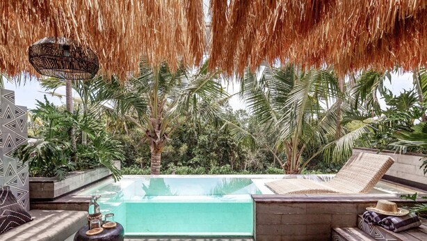 A rooftop infinity pool with lounge chairs and a thatched roof overhead. - Batukaru Private Pool Suite 2 (Canggu)