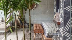 A modern outdoor seating area with a concrete bench, surrounded by tall plants and patterned walls. - Batukaru Private Pool Suite 1 (Canggu)