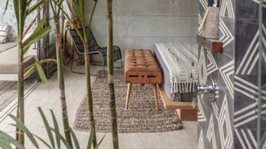 A modern outdoor seating area with a wooden bench and a patterned wall. - Batukaru Private Pool Suite 1 (Canggu)