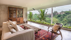 A balcony with a sofa, chair, and a cabinet with glass doors. - Exceptional 2 BR Suites in Ubud Hidden Gem (Ubud)