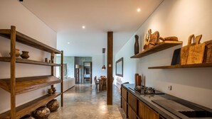 A modern kitchen with wooden shelves displaying pottery and a black countertop with a sink. - Exceptional 2 BR Suites in Ubud Hidden Gem (Ubud)