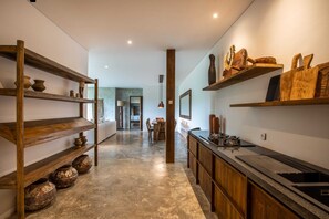 A modern kitchen with wooden shelves displaying pottery and a black countertop with a sink. - Exceptional 2 BR Suites in Ubud Hidden Gem (Ubud)