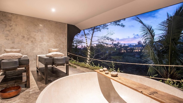 A spa area with a large bathtub, two massage tables, and a wooden shelf with decorative items. - Exceptional 2 BR Suites in Ubud Hidden Gem (Ubud)