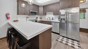 A modern kitchen with a central island, stainless steel appliances, and pendant lighting.