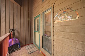 Une véranda en bois avec une valise violette et un balai appuyé contre le mur.