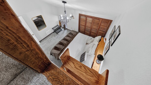 A bedroom with a bed, a nightstand, a mirror, a wardrobe, and a ceiling light fixture.