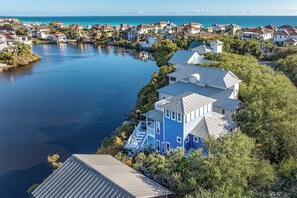 Un quartier résidentiel situé sur la côte, avec des maisons alignées le long du littoral, dont une maison bleue remarquable dotée d’un balcon.