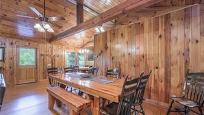 Un comedor de madera con una mesa grande, sillas y un ventilador de techo.