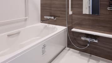 A modern bathroom with a white bathtub, a shower, and a vanity with a mirror.