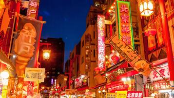 A bustling urban street at night with illuminated signs and traditional lanterns, indicating a vibrant commercial area.