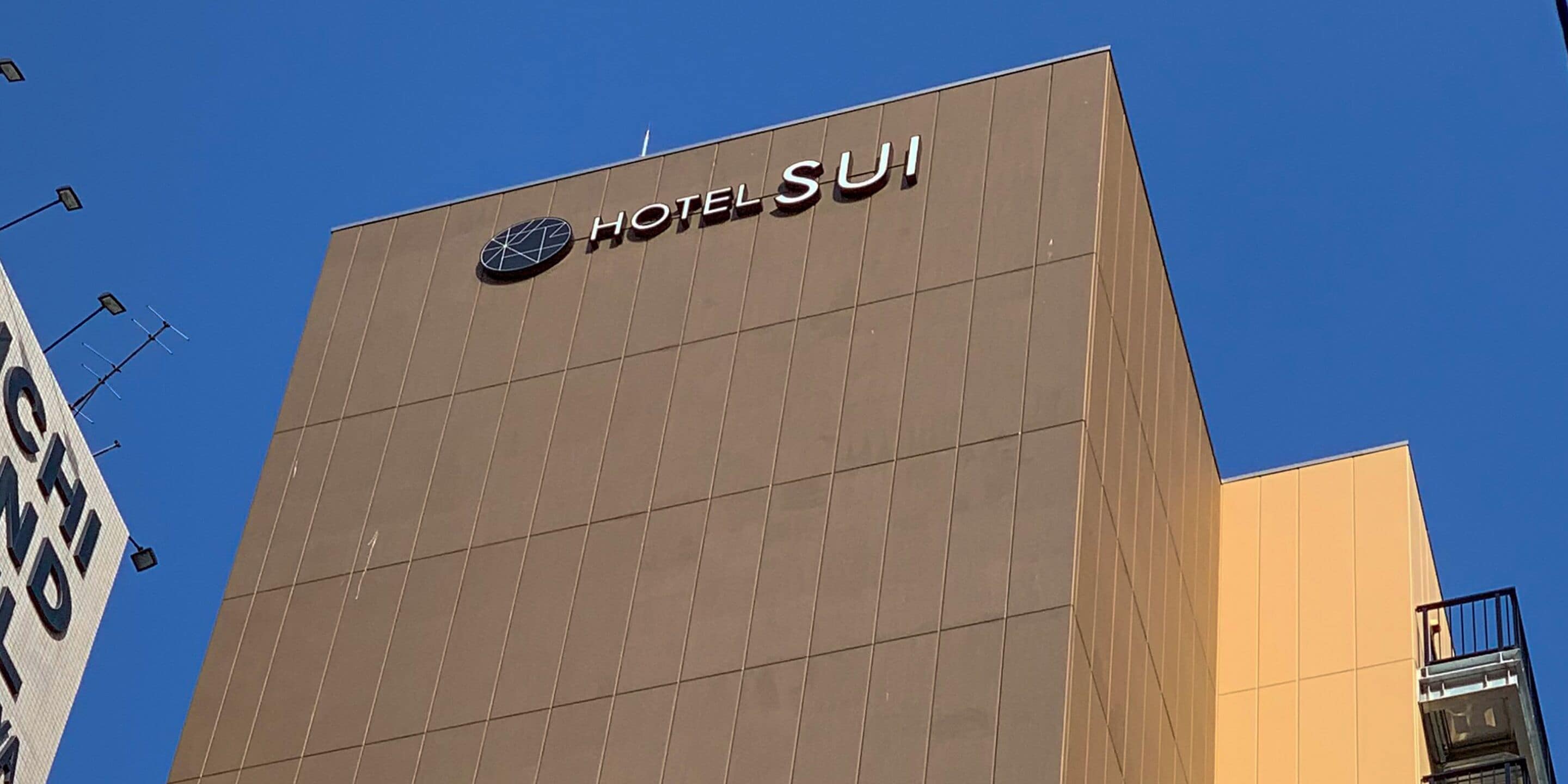 A modern hotel building with a prominent sign reading "HOTEL SUI".