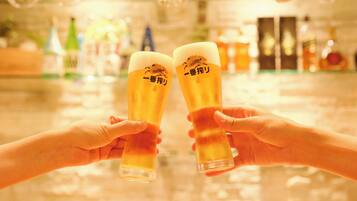 Two hands holding a tall glass with a logo, in a bar setting with bottles in the background.