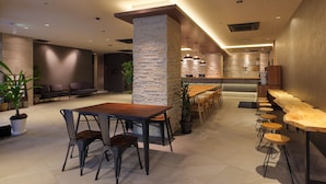 A modern interior with a wooden dining table and chairs, a bar area with stools, and a stone accent wall. - HOTEL SUI KOBE SANNOMIYA by ABEST (Kobe)