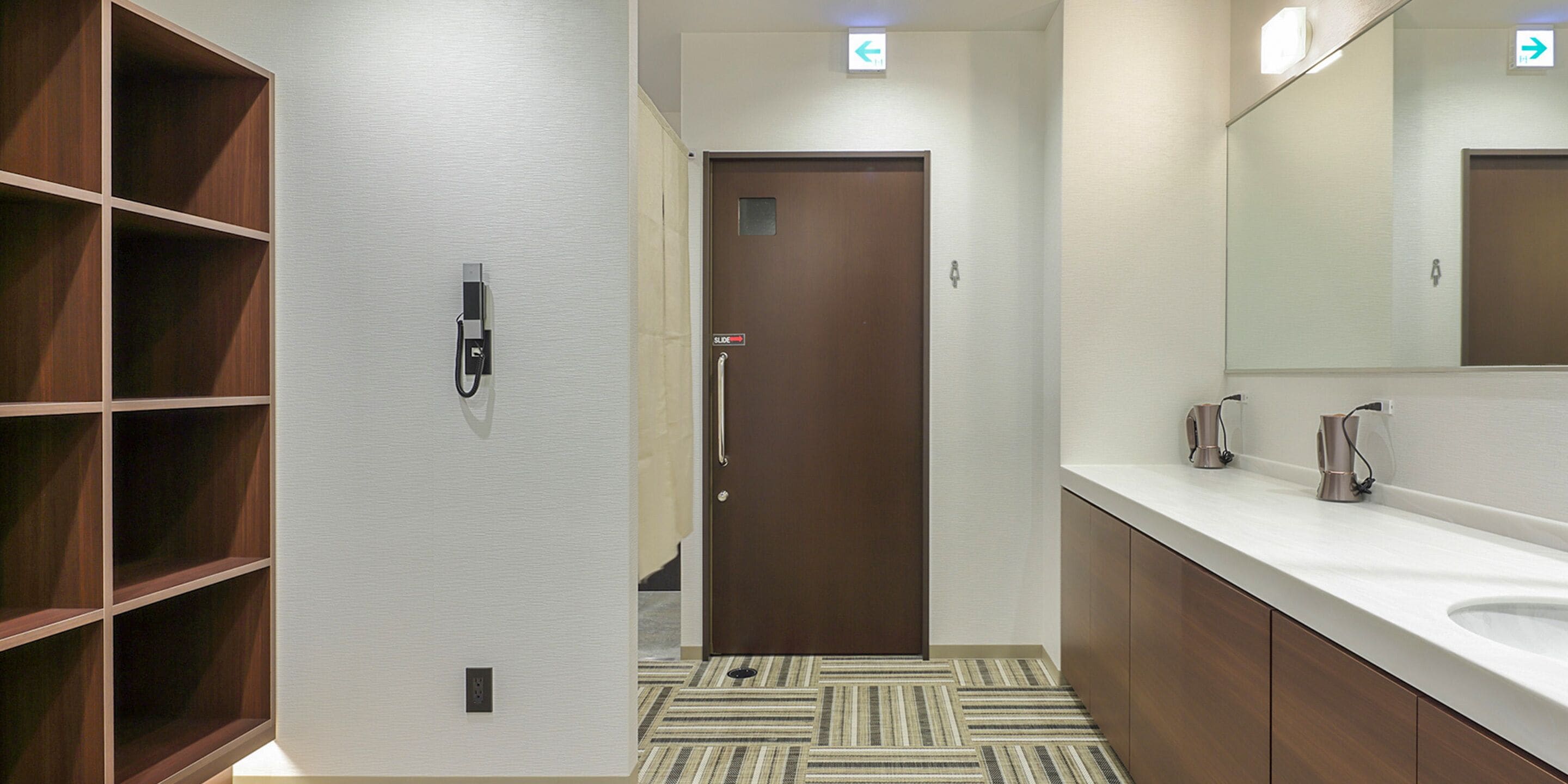 Un baño moderno con tocador de madera, un espejo grande y piso a rayas.