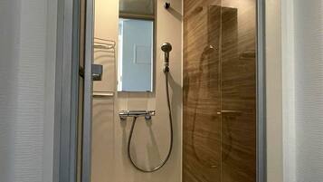 A bathroom with a glass shower enclosure, a handheld showerhead, and a wall-mounted towel rack.