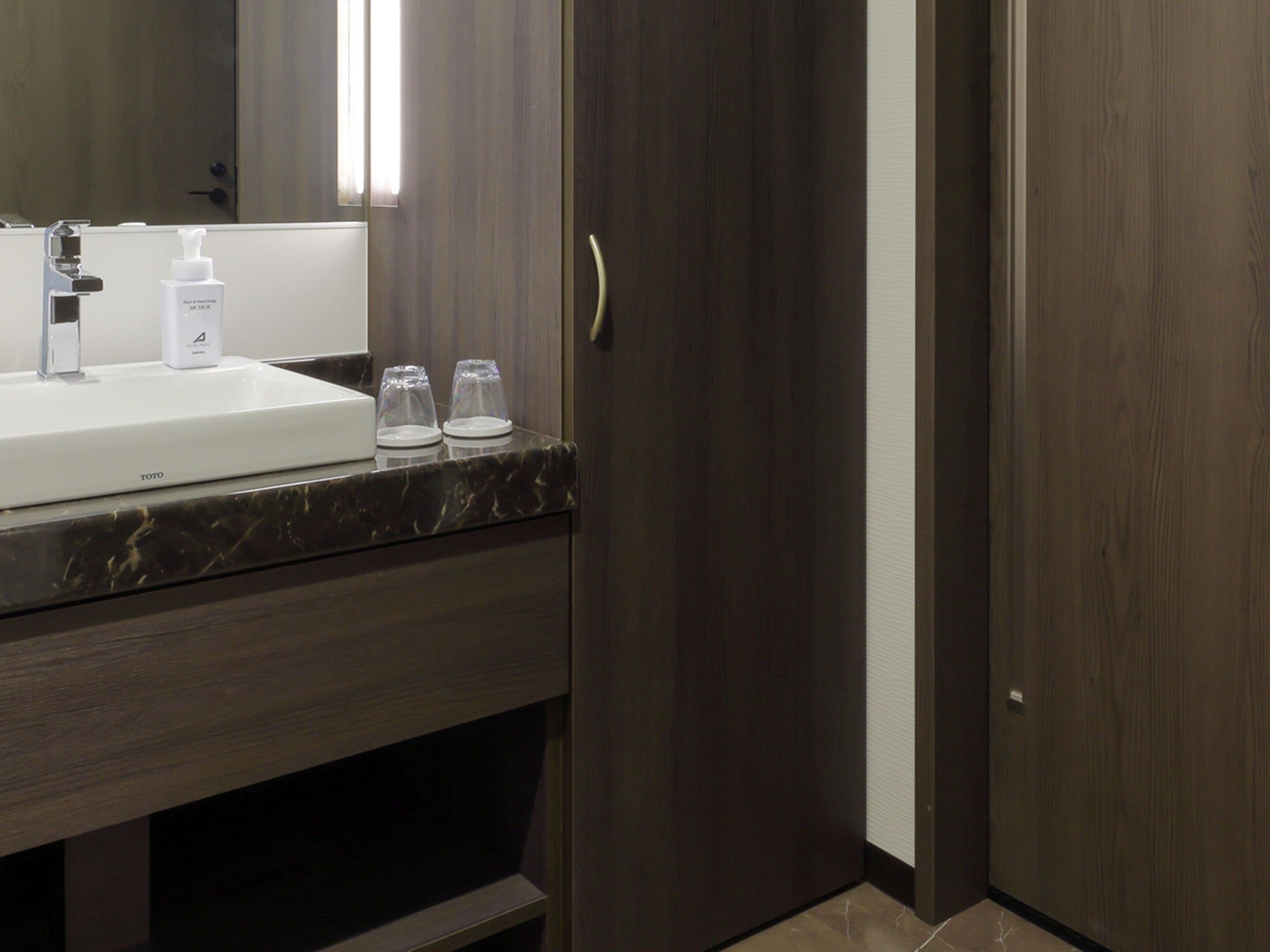 A bathroom with a white sink, a mirror, and a dark wooden door.