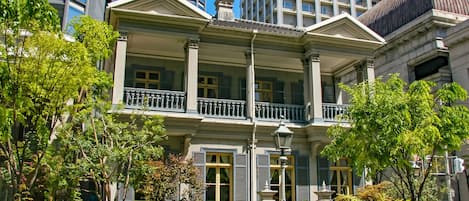 A two-story building with a balcony, columns, and a white picket fence.