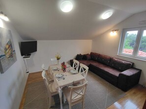 A dining area with a table set for four, a sofa, and a TV mounted on the wall.