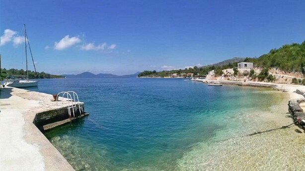 A coastal marina with boats docked, clear waters, and a small building on the shore. - Apartment Kola  (Dubrovacko Primorje)