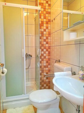 A bathroom with a shower, toilet, and sink.