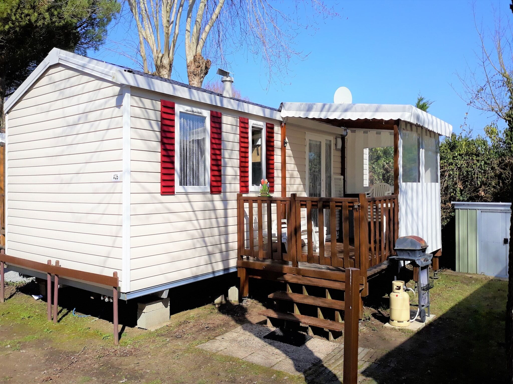 En campingvogn med veranda og en mindre tilbygning.