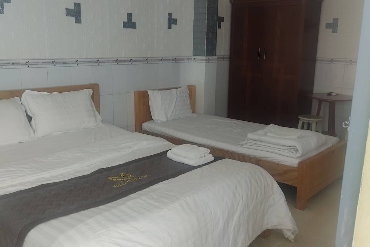 A hotel room with two beds, a wooden wardrobe, and a small table.
