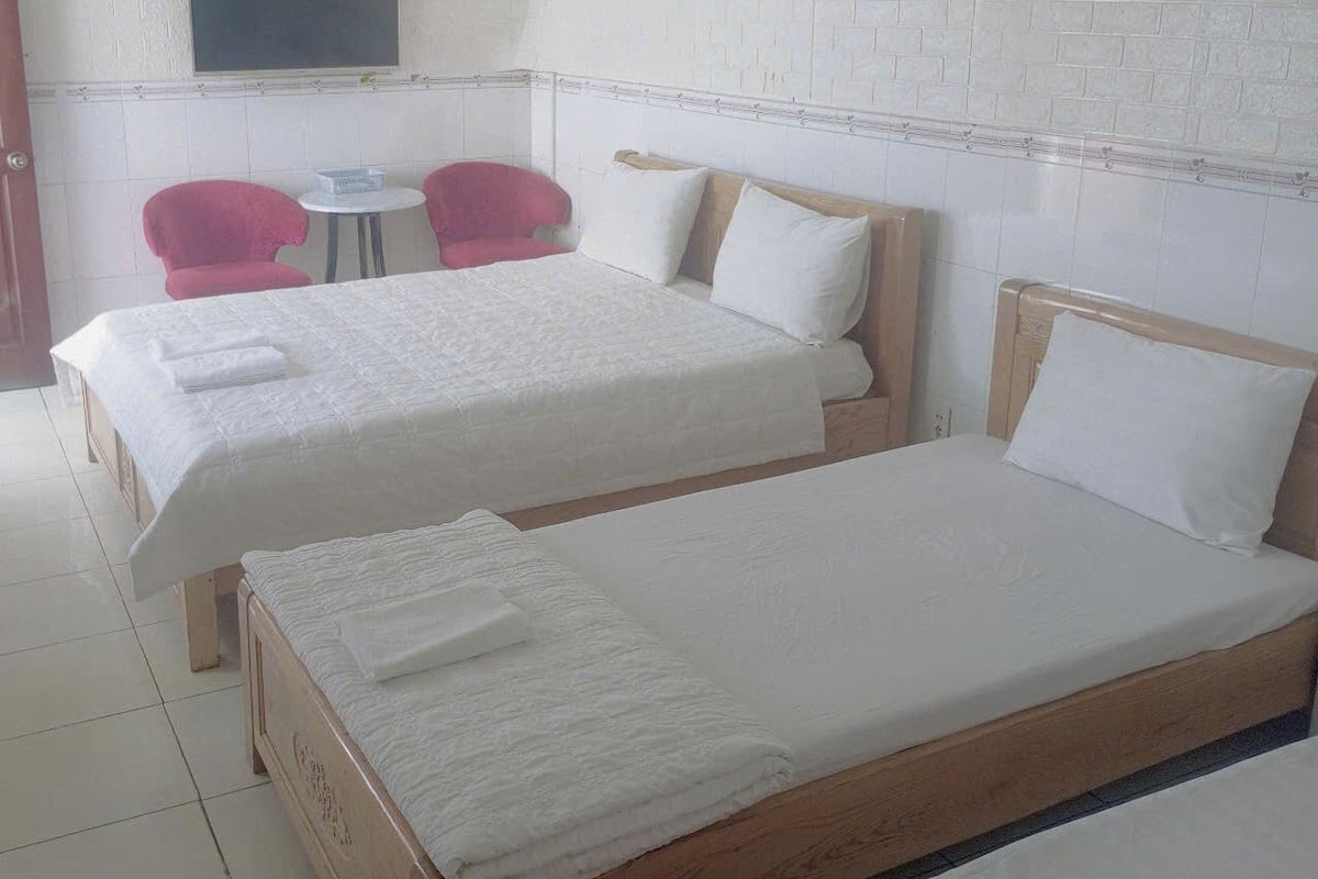 A hotel room with two beds, a television, and a small table with chairs.