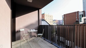 A balcony with a table and chairs, a view of buildings in the background, and a metal fence. - Italianway - Lazzaro Papi 14 B (Milan)