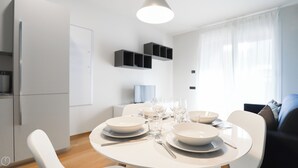A modern dining area with a round table set for four, white plates, and clear glasses. - Italianway - Lazzaro Papi 14 B (Milan)