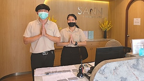 A reception desk with a wooden backdrop and a sign that reads "SANN Boutique Hotel". - Sann Boutique Hotel (Chiang Rai)