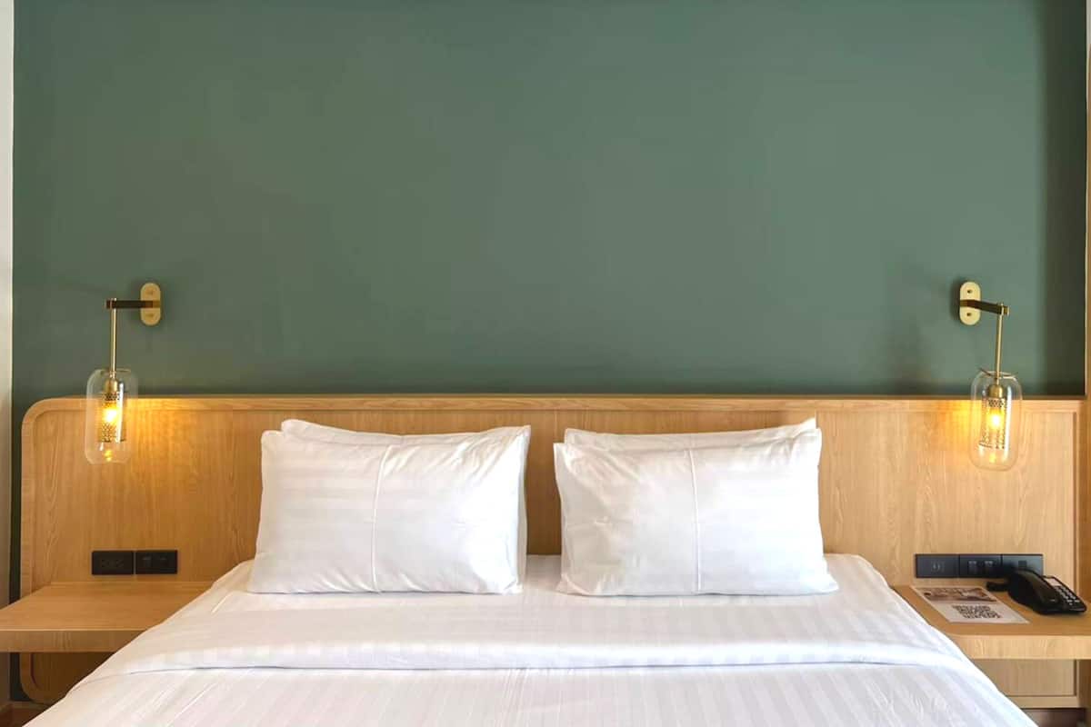 Una habitación de hotel con una cama grande, dos mesitas de noche y una pared verde.