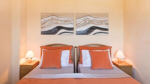 A double bed with orange bedding and white pillows, flanked by two bedside lamps. - Villa Federica by Rodostamo Collection (Corfu)