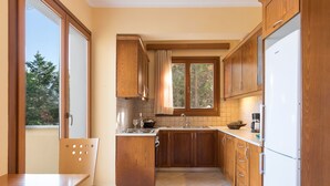 A kitchen with wooden cabinets, a sink, a stove, and a refrigerator. - Villa Federica by Rodostamo Collection (Corfu)