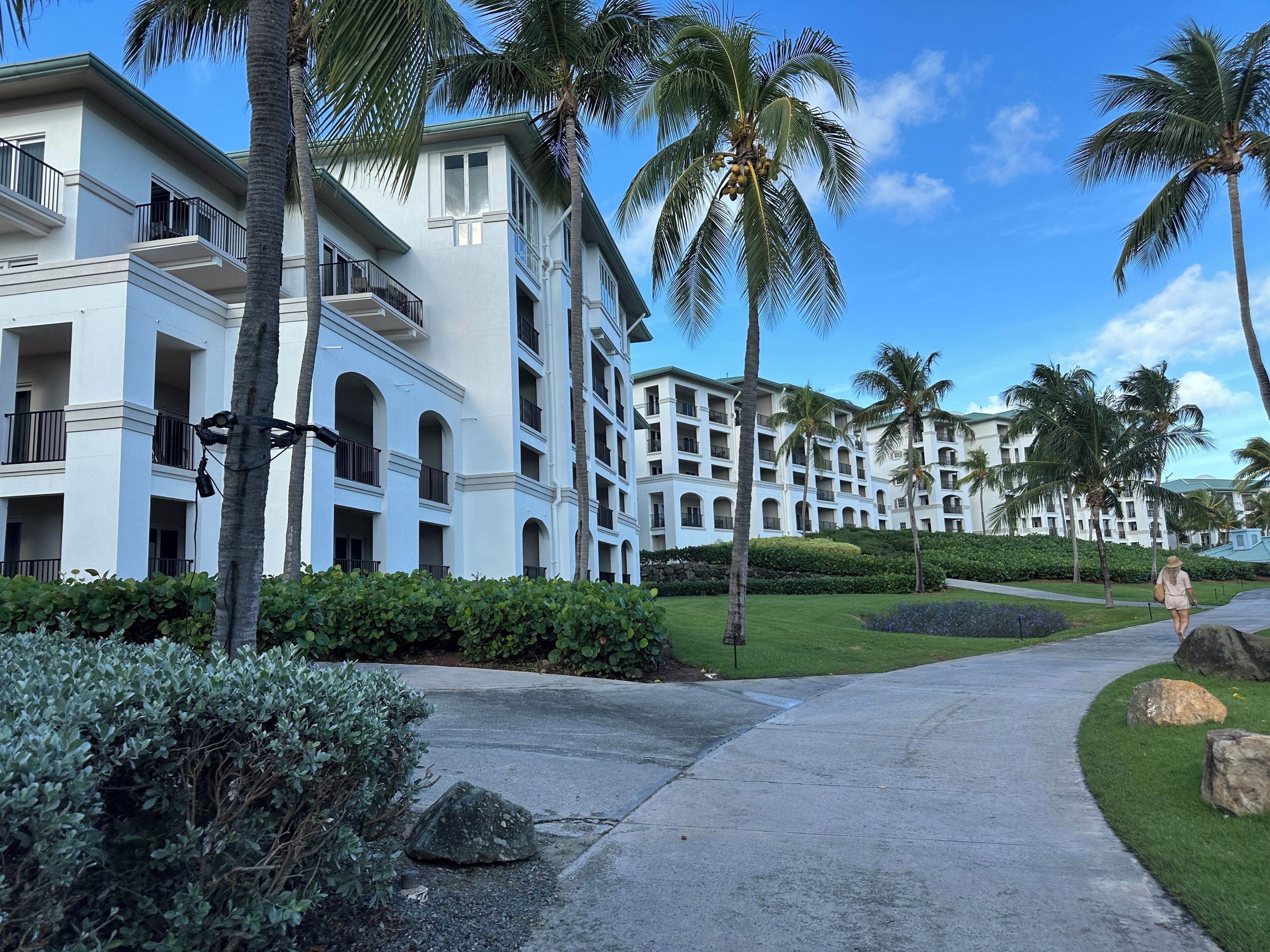 A resort with multi-story buildings, palm trees, and a paved walkway.