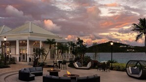 A resort with outdoor seating, a pool, and a view of the sea at sunset. - BEACHFRONT LUXURY at the Ritz! NEWLY RENOVATED - MOST DATES Available! (St Thomas)