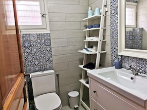 Ein Badezimmer mit Toilette, Waschbecken und Regalen mit Pflegeprodukten.